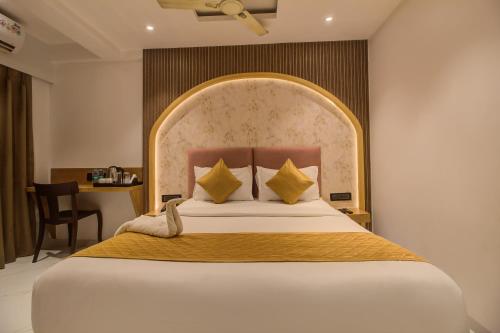 a bedroom with a large bed and a desk at Hotel Malad Inn opposite Malad Railway Station in Mumbai