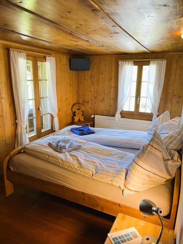 a large bed in a room with wooden walls and windows at BnB Haus Itten in Hondrich