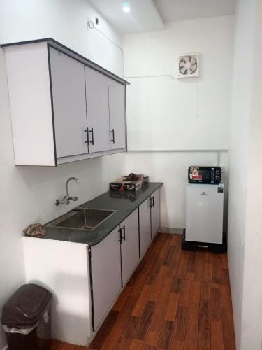 a kitchen with white cabinets and a sink and a refrigerator at BIA RESIDENCEs in Sāhīwāl