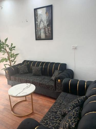 a living room with a black couch and a table at BIA RESIDENCEs in Sāhīwāl