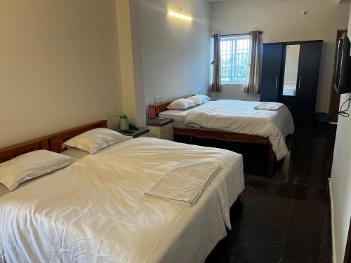 a hotel room with two beds and a window at Sansav Garden Resort in Gurpur