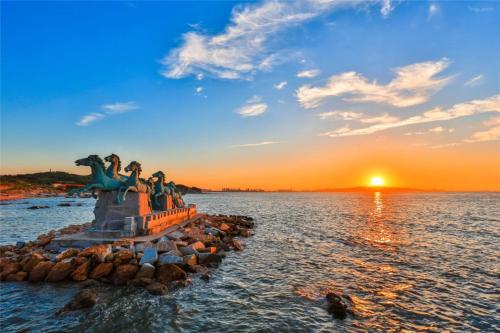 a statue in the water with a sunset in the background at JOYSEA HUT in Yantai