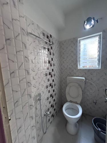 a bathroom with a toilet and a shower with a window at OhanaStay02 in Guwahati