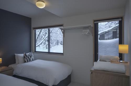 a bedroom with a bed and a window with snow outside at Hakuba Cottage Karamatsu in Hakuba