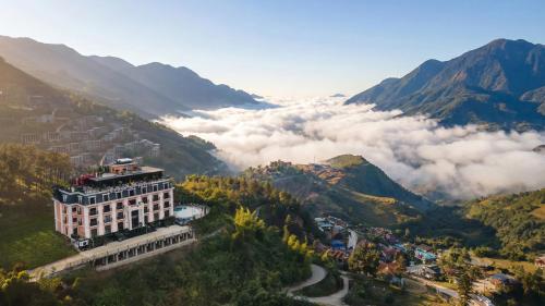 a building on top of a mountain with clouds at DeLaMont Sapa Hotel - Hill Serenity Retreat in Sapa