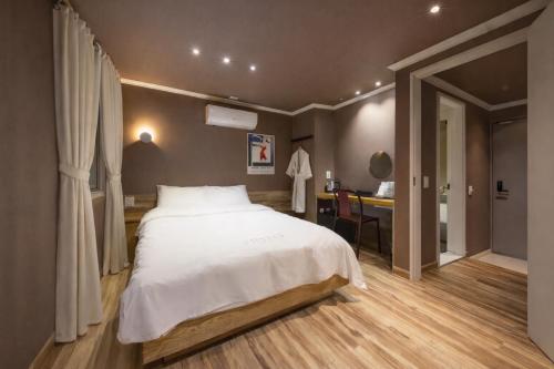 a bedroom with a large white bed and a desk at Tinto Hotel Busan Station in Busan