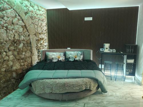 a bedroom with a large bed with a stone wall at Suite San Giovanni in Gela