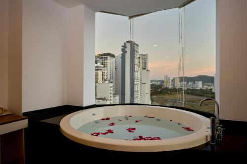 a bath tub in a room with a large window at The Sol Hotel in Nha Trang