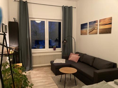 a living room with a black couch and a window at Direkt am Südstrand! in Wilhelmshaven