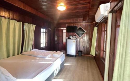 a small bedroom with a bed and a refrigerator at Oh Taley Resort in Rayong