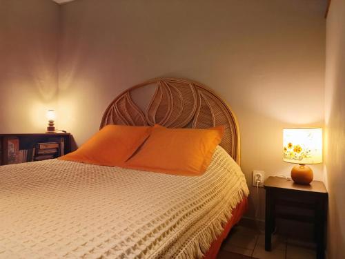 a bedroom with a bed with an orange pillow on it at Les Jardins d'Arbousse in Saint-Jean-du-Gard