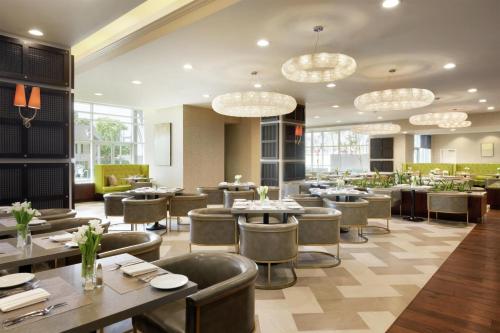 a restaurant with tables and chairs and chandeliers at Embassy Suites Los Angeles Glendale in Glendale