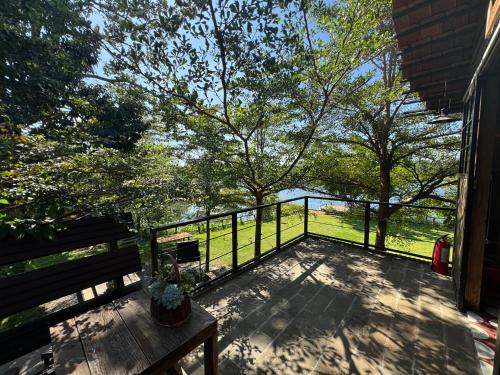 a deck with a bench and a fence and trees at The Forester Chalet in Buôn Pưk Prong