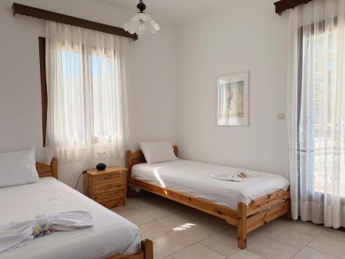 two beds in a room with white walls and windows at Xenius Zeus Apartments in Kriopigi in Kriopigi