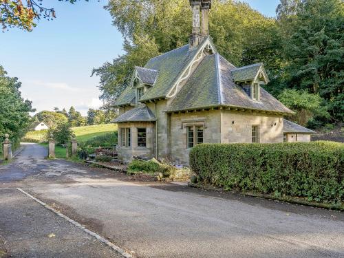an old stone house with a chimney on a street at East Lodge in Falkland