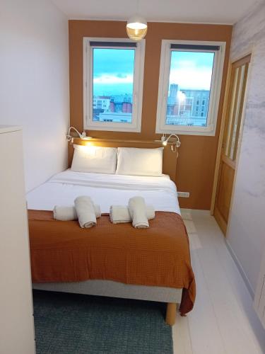 a bedroom with a bed with two pillows and two windows at La parenthèse 70's in Le Havre