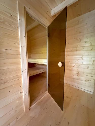 a sauna with wood paneling and a glass wall at Camping Héiltzerstee in Rambrouch