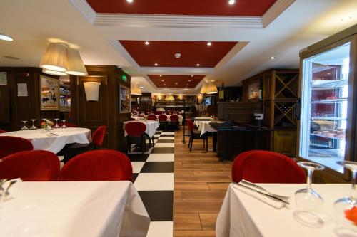 ein Restaurant mit weißen Tischen und roten Stühlen in der Unterkunft Grand Hôtel d'Espagne in Lourdes