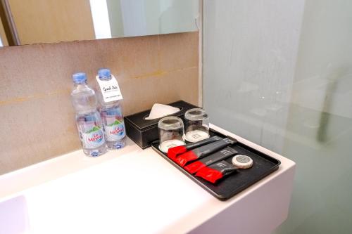 a bathroom counter with bottles of water and batteries at Grand Zuri Malioboro in Yogyakarta