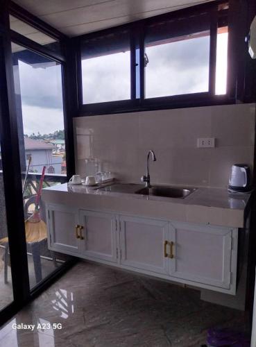 a kitchen with a sink and two windows at Buddy's Skybar & Suite in Guinsorongan