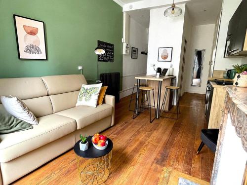 a living room with a couch and a table at Charmant studio aux beaux volumes in Dreux