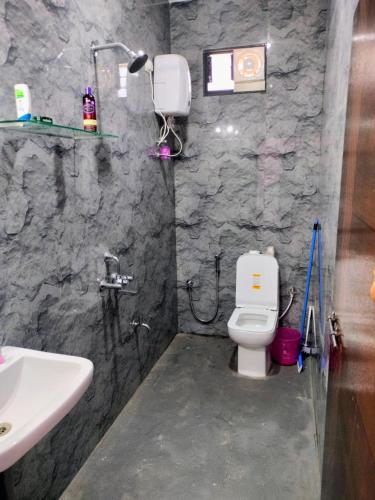 a bathroom with a white toilet and a sink at Tree hugs mandrem in Mandrem