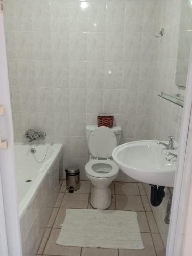 a white bathroom with a toilet and a sink at Bloemhoek Guest House in Centurion