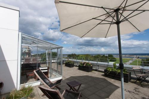 a patio with chairs and an umbrella on a balcony at Beach Penthouse Amagerstrand in Copenhagen