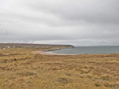 a grassy field with a beach and the ocean at Ken Maree in South Erradale