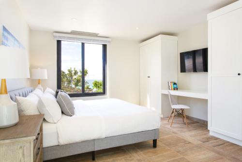 a bedroom with a bed and a desk and a window at Sandcastle Beach House in The Valley