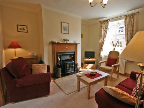 a living room with a fireplace and a couch and chair at Cosy Cottage in Warkworth