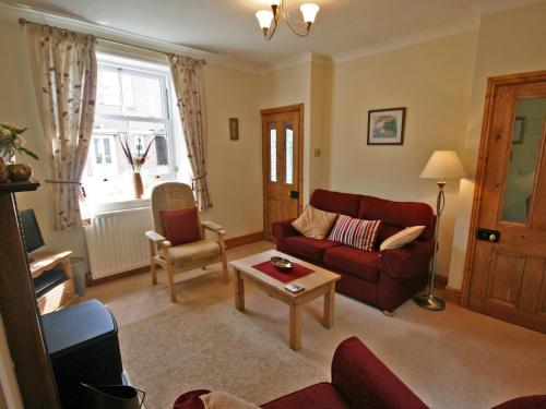 a living room with a red couch and a table at Cosy Cottage in Warkworth