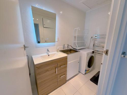a bathroom with a sink and a washing machine at Bright Eden Park two bed townhouse private parking in Auckland