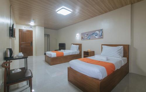 a hotel room with two beds and a television at Algers Suites Bayan-Bayanan Marikina City in Manila