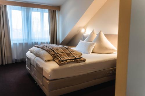 a bedroom with a bed with pillows and a window at Hotel Villa Will in Hannover