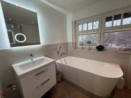 a white bathroom with a tub and a sink at Villa Strandleben in Zingst