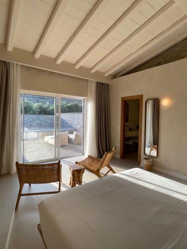a bedroom with a large bed and a large window at Melitsina Village Hotel in Kardamyli
