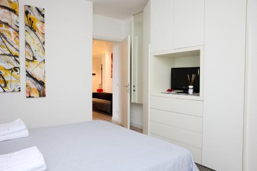 a white bedroom with a bed and a tv at Art-inn in San Vendemiano