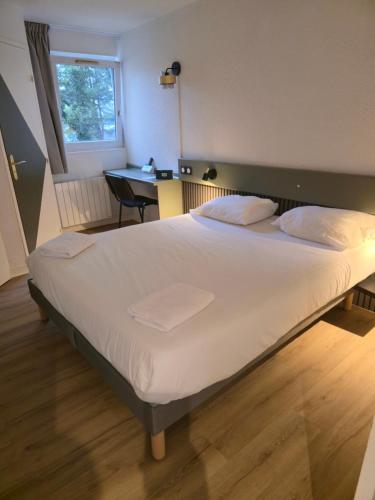 ein großes Bett in einem Zimmer mit Schreibtisch in der Unterkunft Logis Hôtel Come Inn in Poitiers