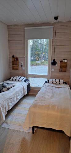 two beds in a room with a window at Levi Lakeview Ahvenranta in Kittilä