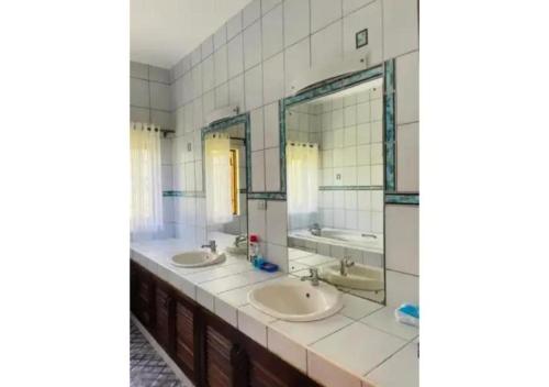 a bathroom with two sinks and two mirrors at Mango Villa Mtwapa in Mtwapa