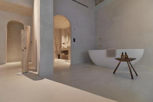 a white bathroom with a tub and a table at Hotel Avenida in Zaragoza