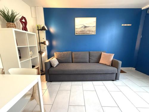 a couch in a living room with a blue wall at Appart' Lumineux & Chic. Parking Rue Sans Stress in Dreux