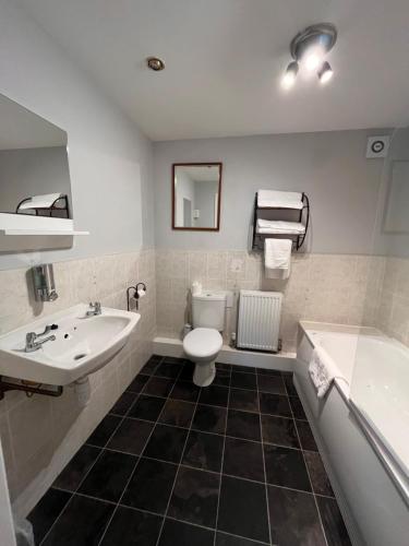 a bathroom with a sink and a toilet and a tub at Pendle Inn in Barrowford