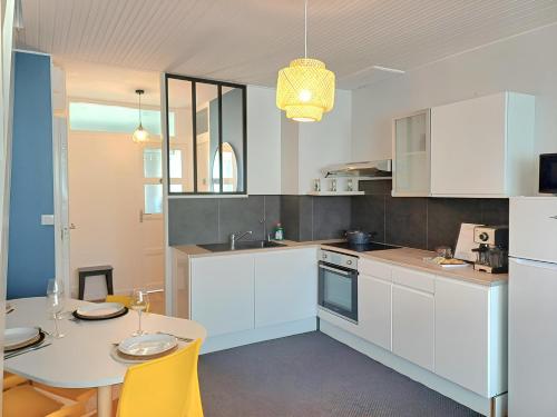 a kitchen with white cabinets and a table with yellow chairs at Le Loft - En Plein Centre Très Spacieux in Beauvais