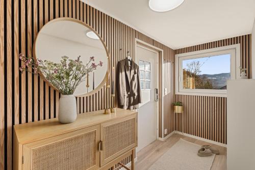 a hallway with a mirror and a vase with flowers at Aurora Bliss - Waterfront Jacuzzi & Sauna near Bergen in Askøy