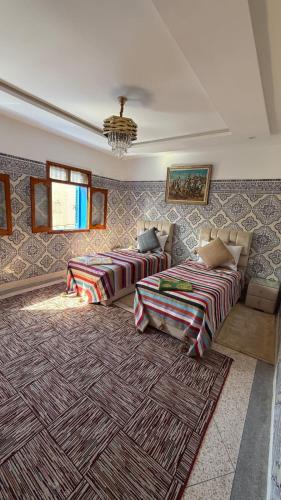a living room with two beds and a rug at Résidence chez Said in Sidi Ifni