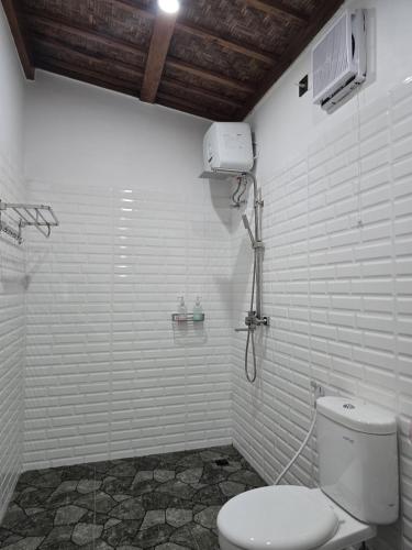 a white bathroom with a toilet and a shower at Rice Terrace Bungalows in Tetebatu