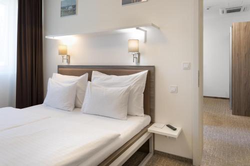 a bedroom with a bed with white sheets and pillows at SKY Hotel Prague in Prague