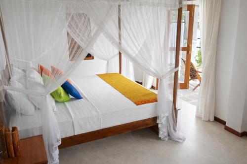 a bedroom with a canopy bed with white drapes at Cinnamon Villas in Ambalangoda